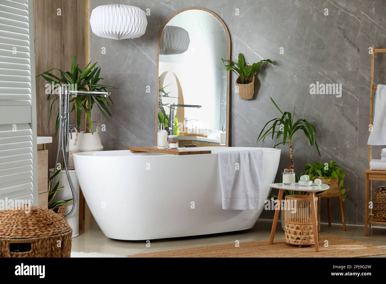 Modern white tub and beautiful green houseplants in bathroom. Interior ...
