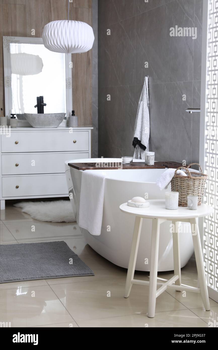 Modern white tub and table with toiletries in bathroom. Interior design ...