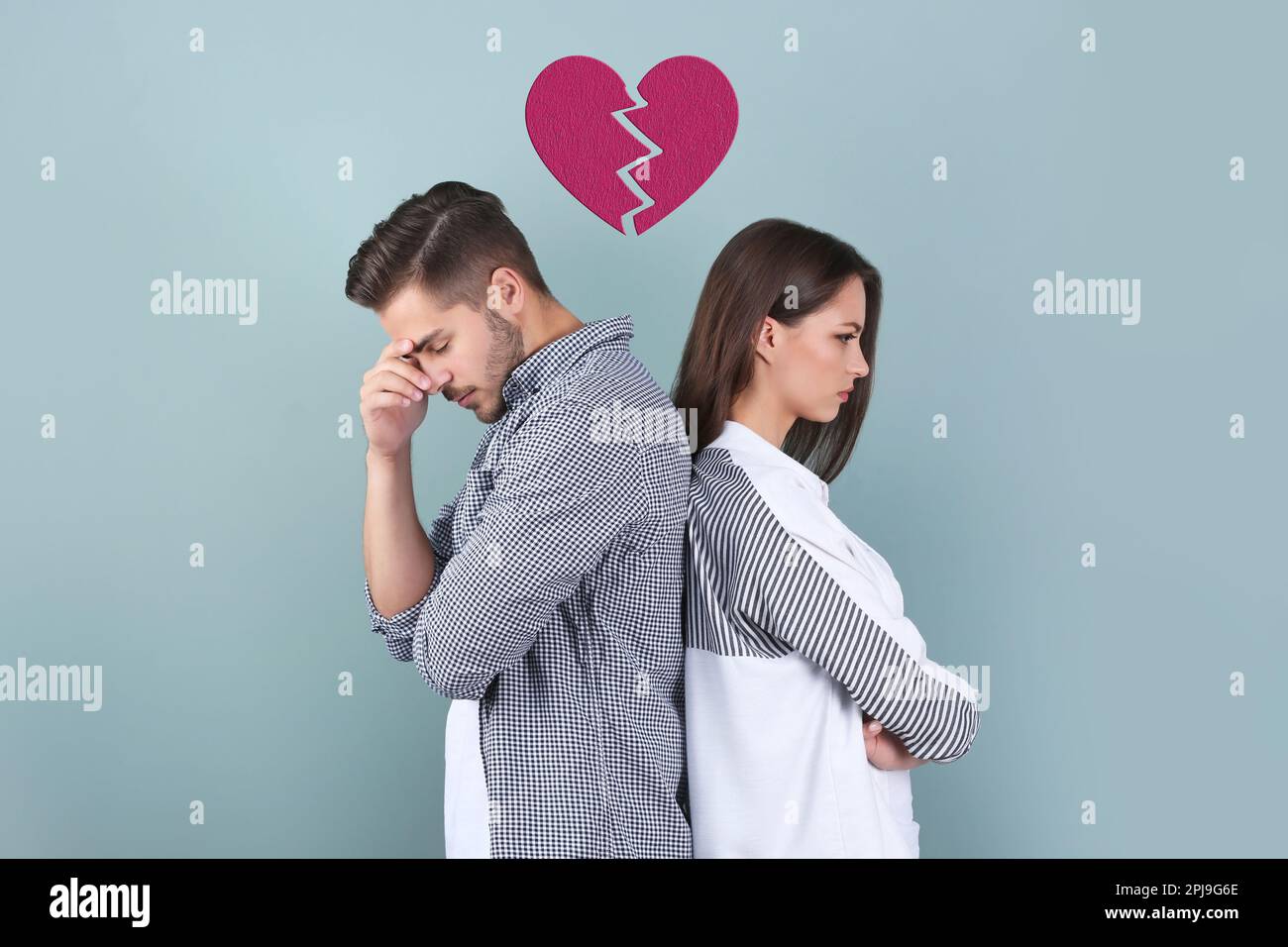 Upset young couple and illustration of broken heart on color background. Relationship problems Stock Photo