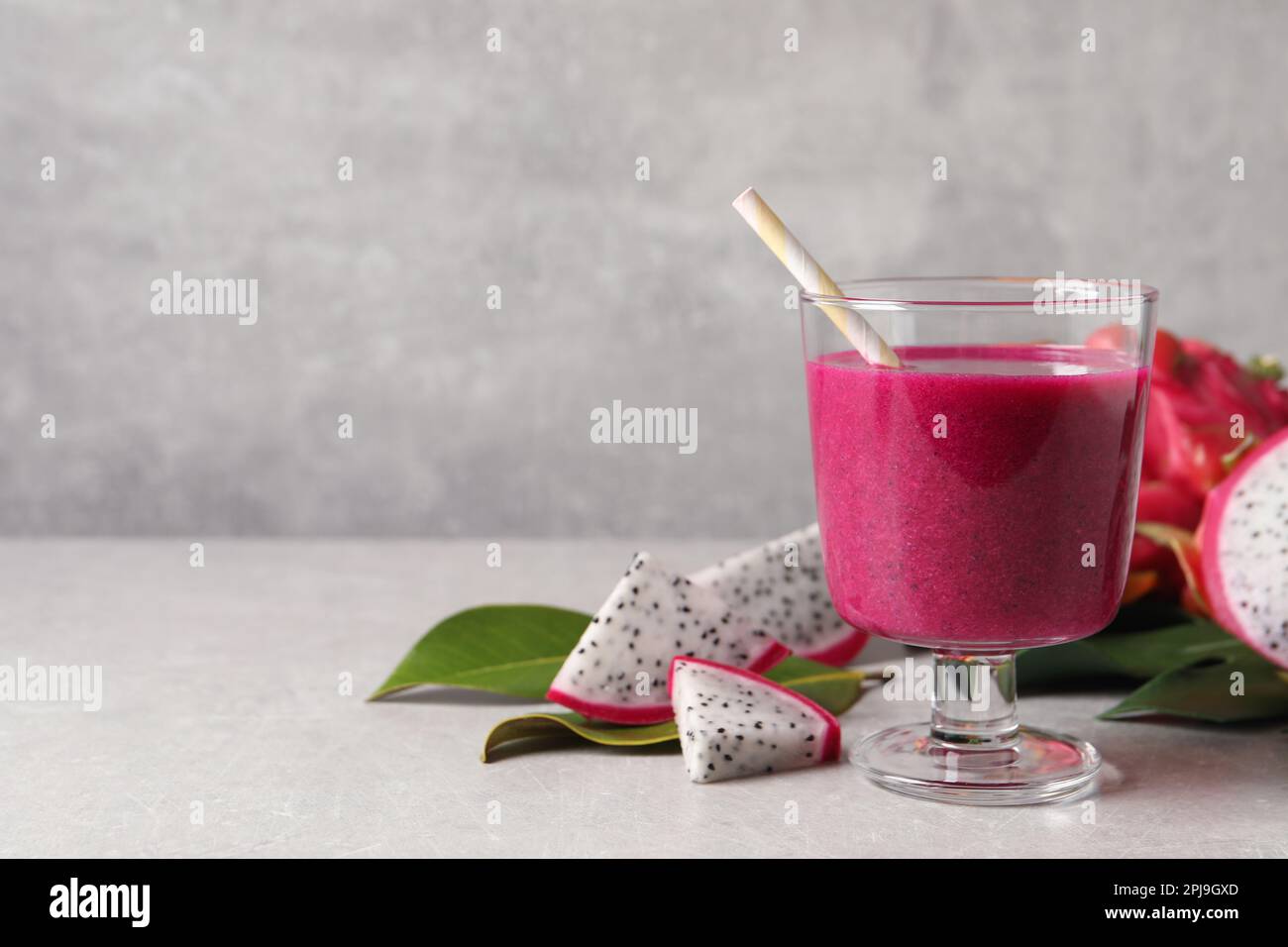 Delicious pitahaya smoothie and fresh fruits on light grey table, space ...
