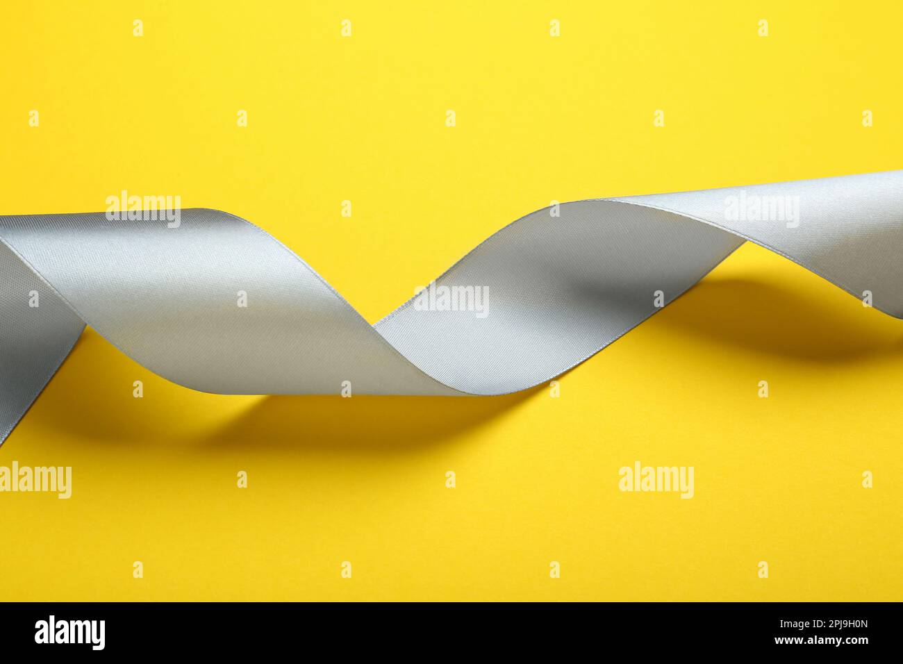 Beautiful ribbon on yellow background, closeup view Stock Photo - Alamy