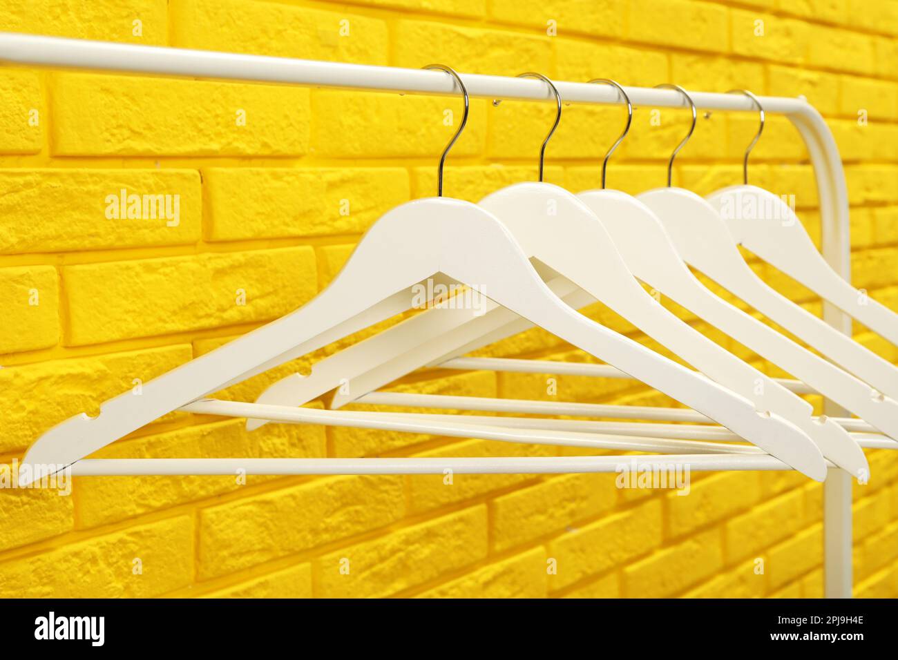 Wardrobe rack with many hangers near yellow brick wall Stock Photo Alamy