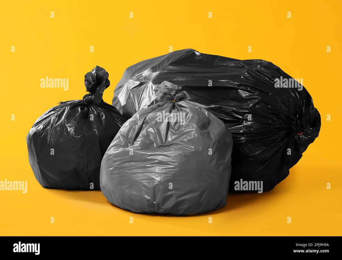 https://c8.alamy.com/comp/2PJ9H9A/trash-bags-full-of-garbage-on-yellow-background-2PJ9H9A.jpg