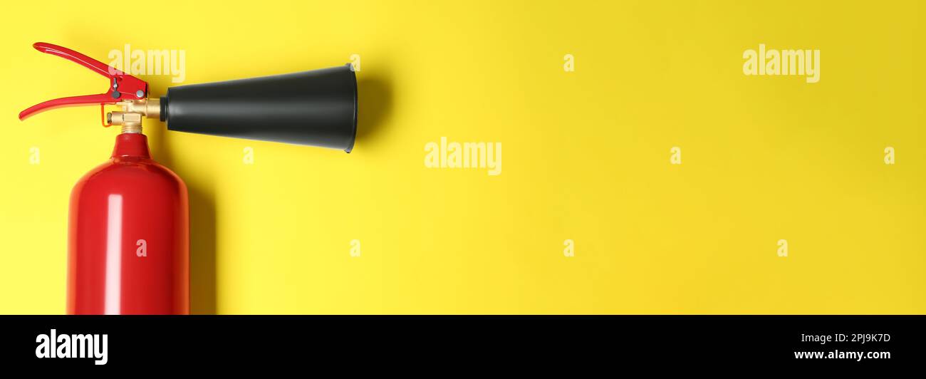 Fire extinguisher on yellow background, top view with space for text