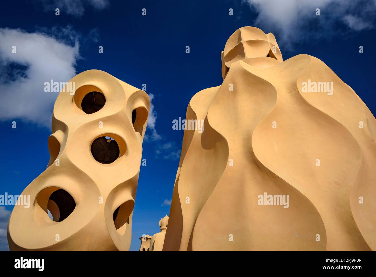 Stairwell topped with curved shapes and the 4-armed cross designed by Gaudí on the roof terrace of Casa Milà - La Pedrera, Barcelona Catalonia Spain Stock Photo