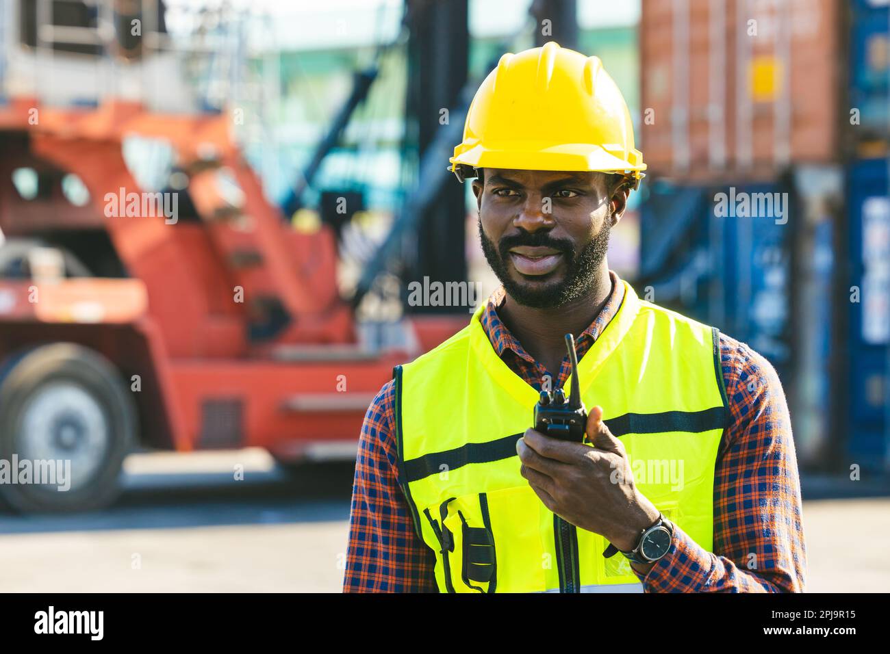 african black male worker foreman work cargo control loading operator in container shipping dock yard Stock Photo