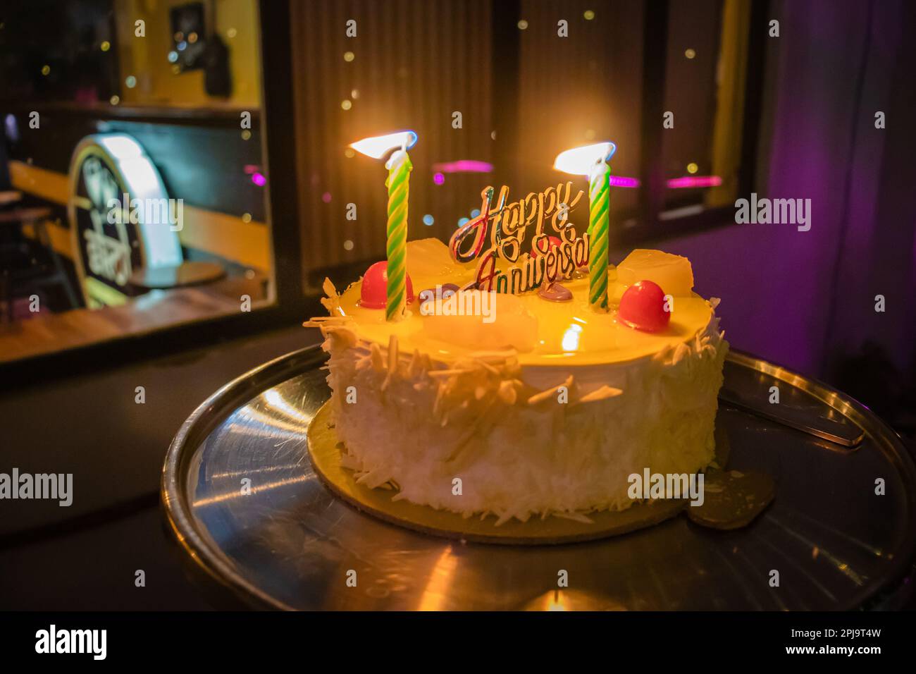 anniversary party white pine apple cake with candle at night from flat angle Stock Photo