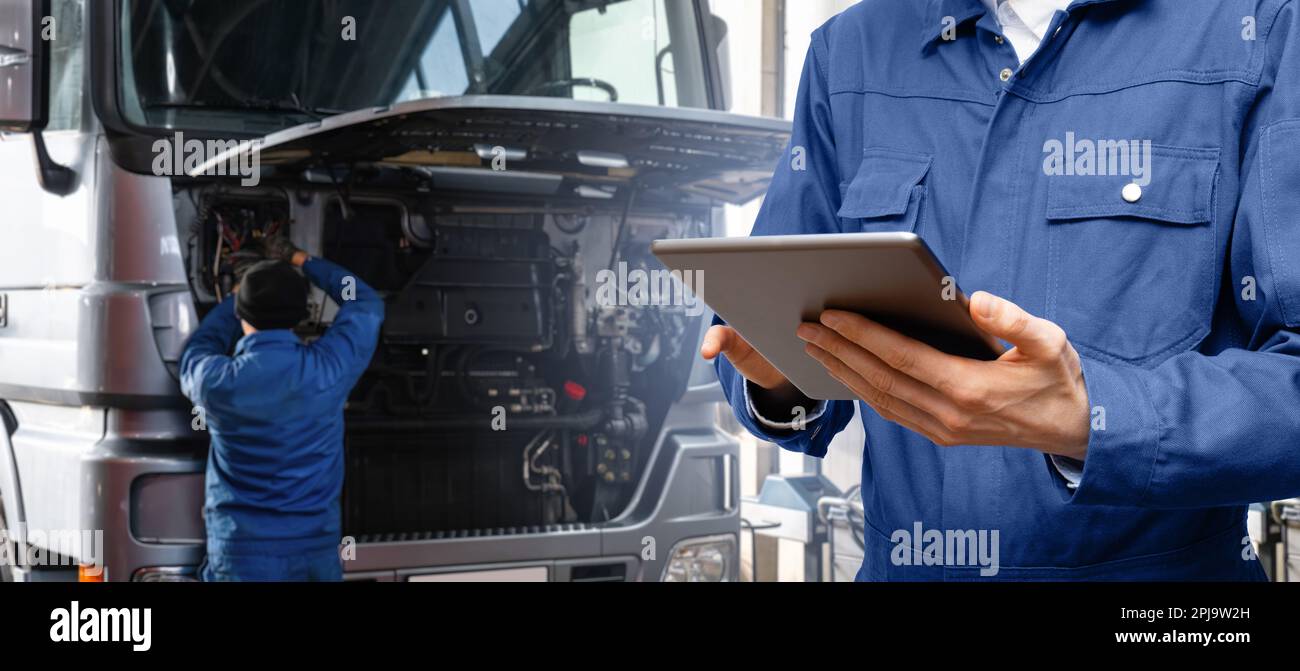 Serviceman with digital tablet on the background of the truck in the car service. High quality photo Stock Photo