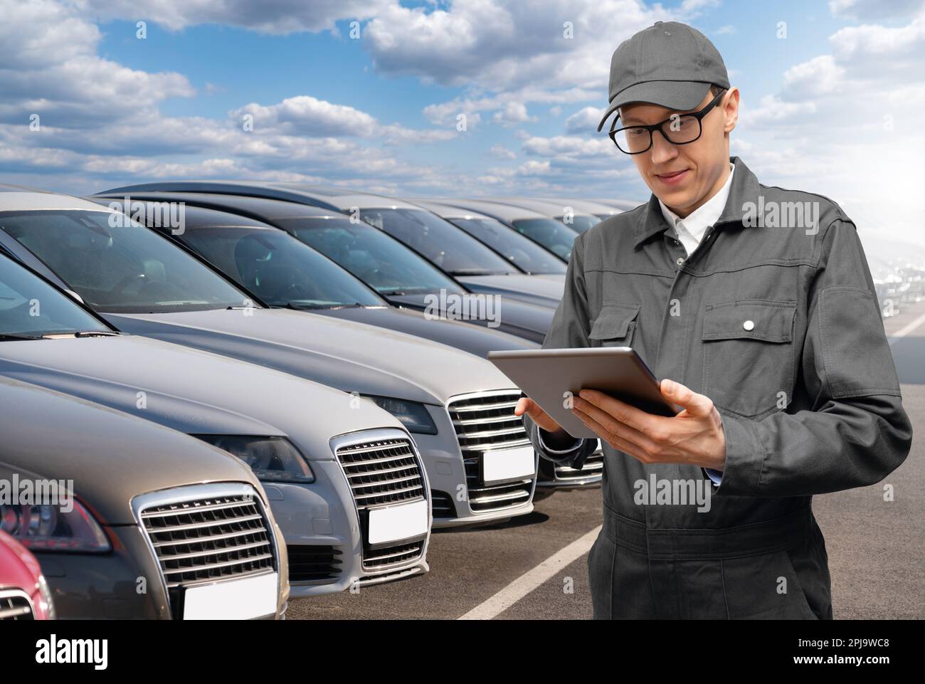 Manager with digital tablet on a background of rows of cars. Car sales. Stock Photo