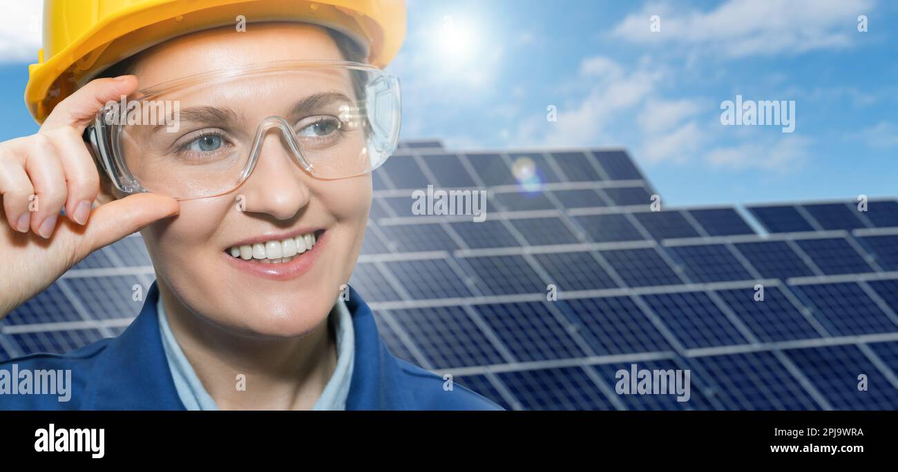 Portrait of a woman engineer in helmet and protective glasses on a background of solar energy power station.. High quality photo Stock Photo