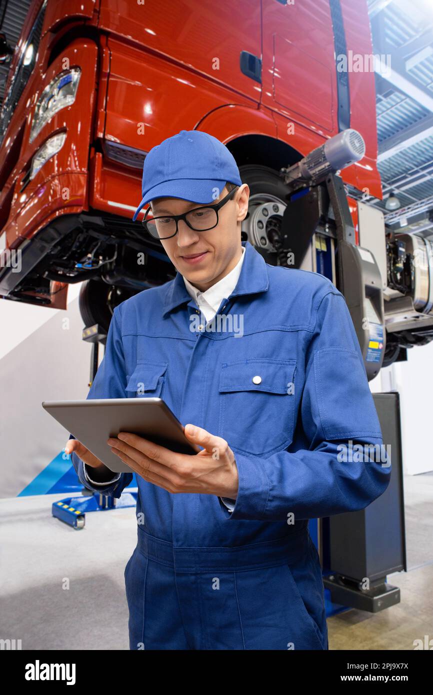 Serviceman with digital tablet on the background of the truck in the car service. High quality photo Stock Photo