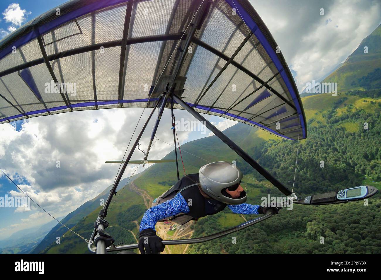 Girl hang glider pilot soars in the mountains on her light kite wing