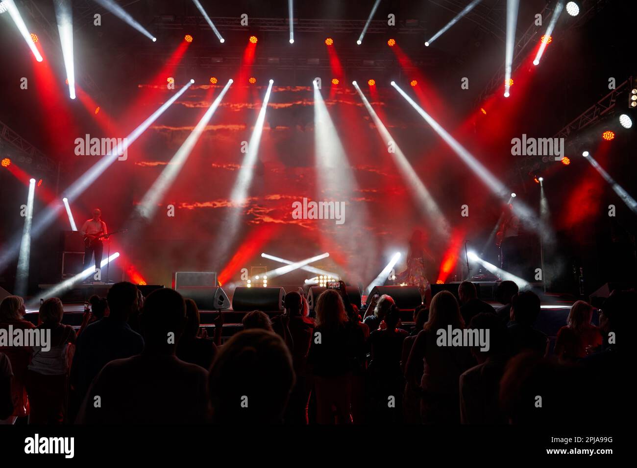 Colourful concert arena with a crowd silhouette against stage lights. silhouettes of the audience against the background of the concert stage Stock Photo