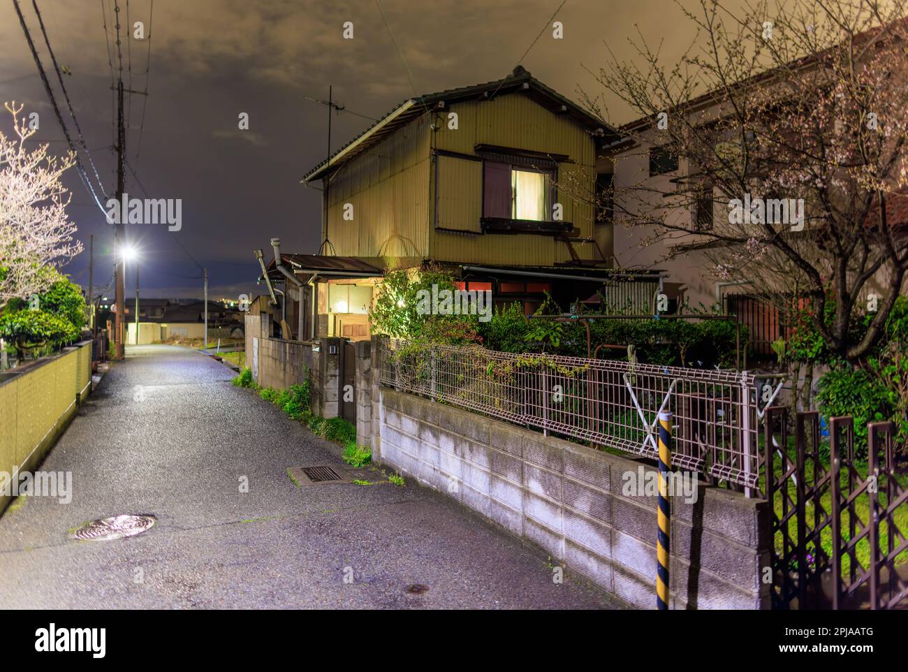 Lights in Japanese house on quiet street in residential neighborhood at night Stock Photo