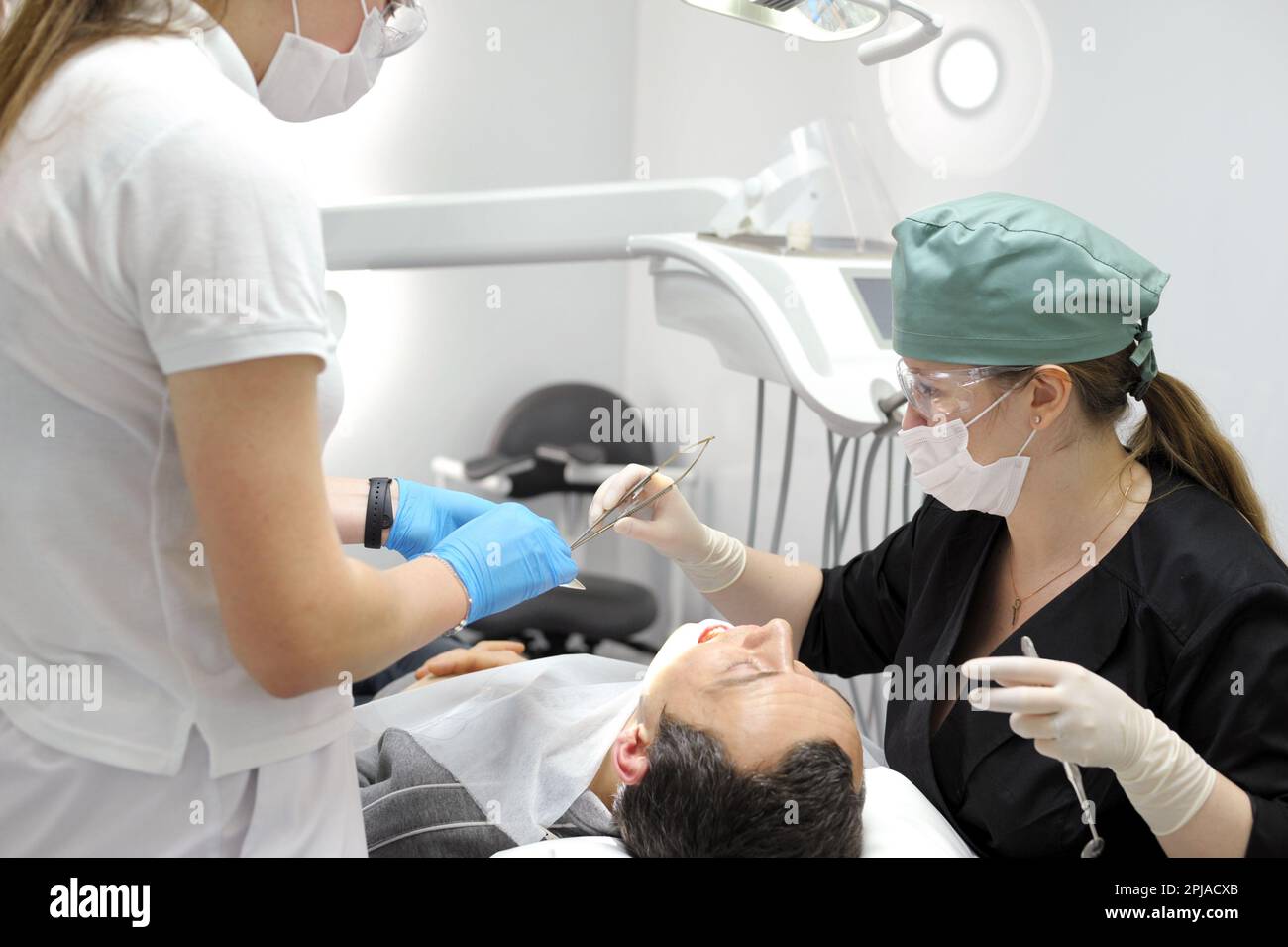 Surgery in a dental clinic. The dentist surgeon stitches the wound in