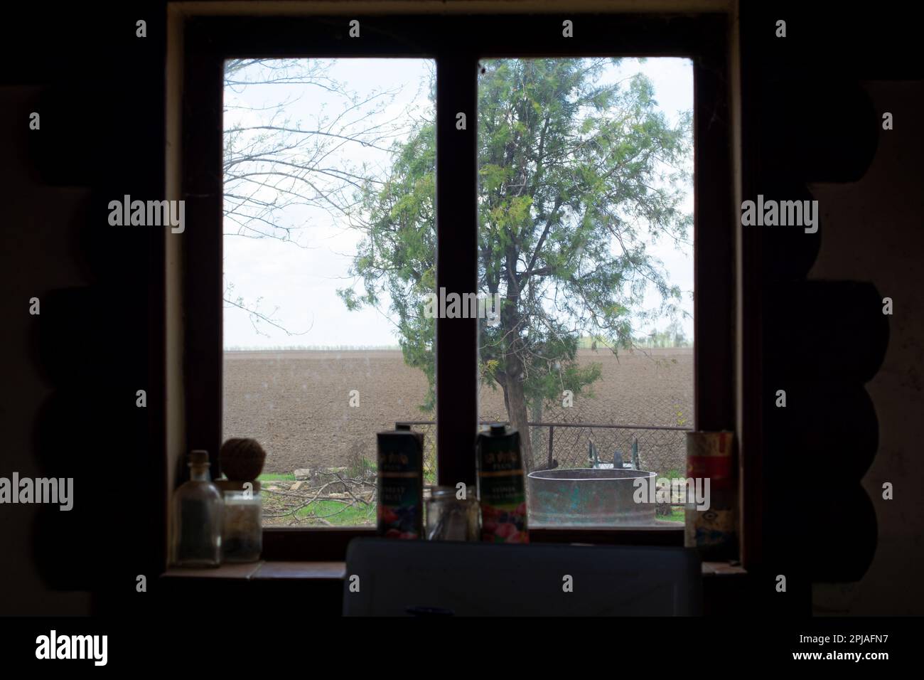 A view from a window of a dilapidated Vojvodinian farmhouse at the Pannonian plane. Focus on the plain. Stock Photo