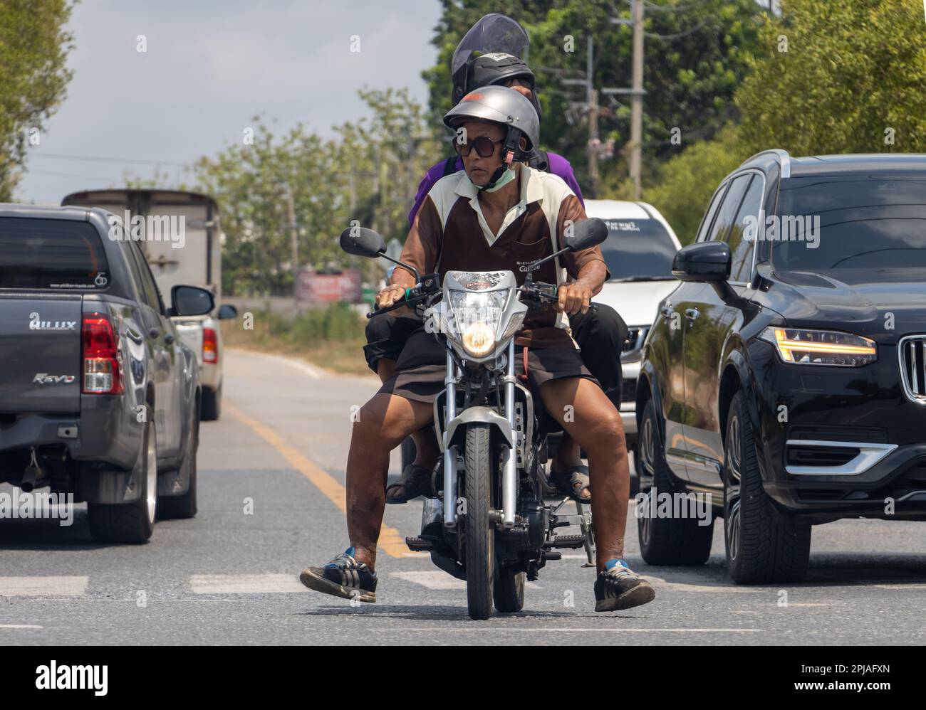 BANGKOK, THAILAND, MAR 24 2023, Two men on a motorcycle cautiously enter a suburban intersection Stock Photo