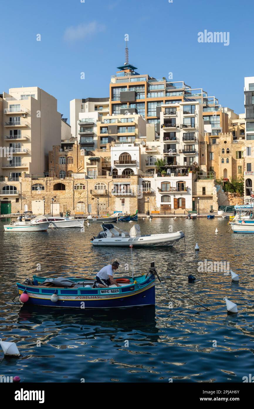 Fishing boat and fisherman in Spinola Bay in Saint Julian's with it many apartments, Malta, Europe Stock Photo