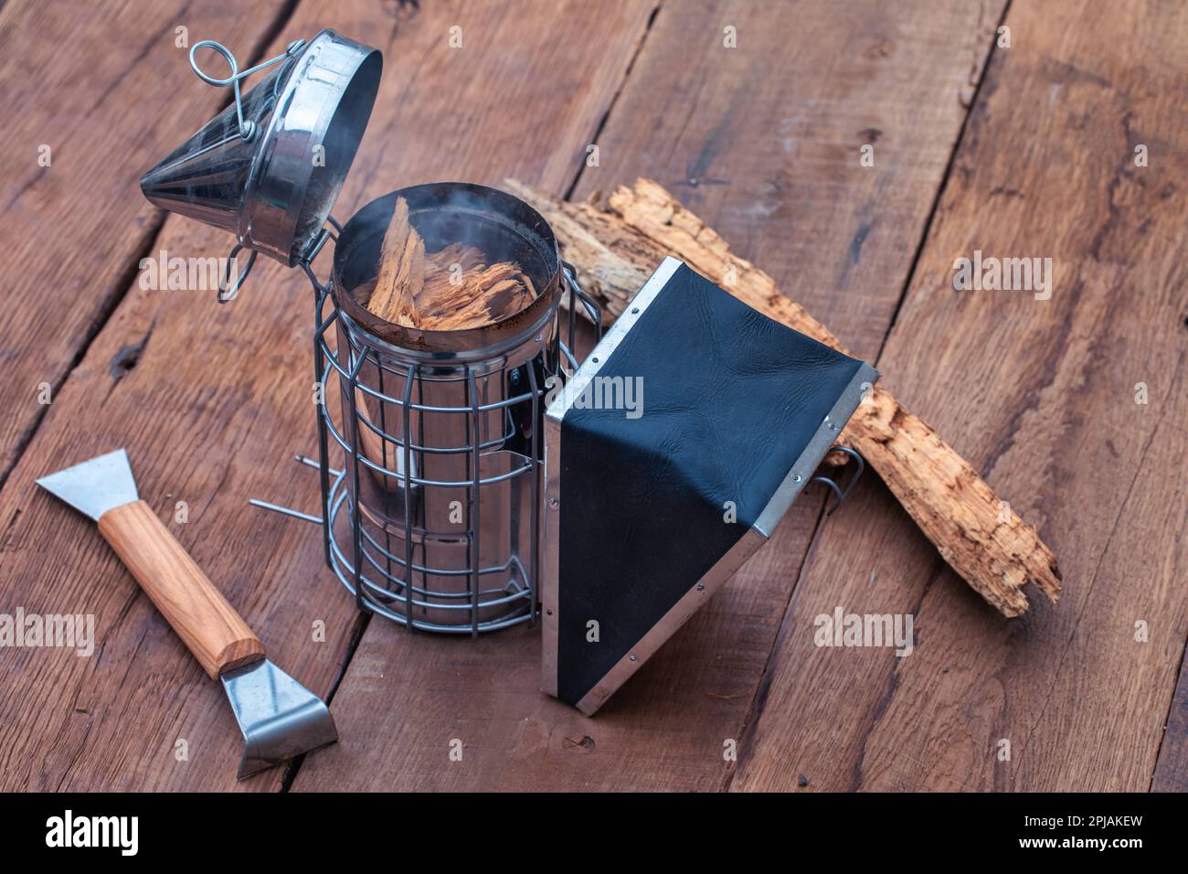The set also comes with a smoker, hive tool, and bee brush, all neatly arranged on a wooden table. Stock Photo