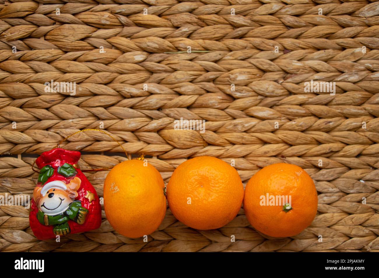 Christmas toy with tangerines on a straw background Stock Photo