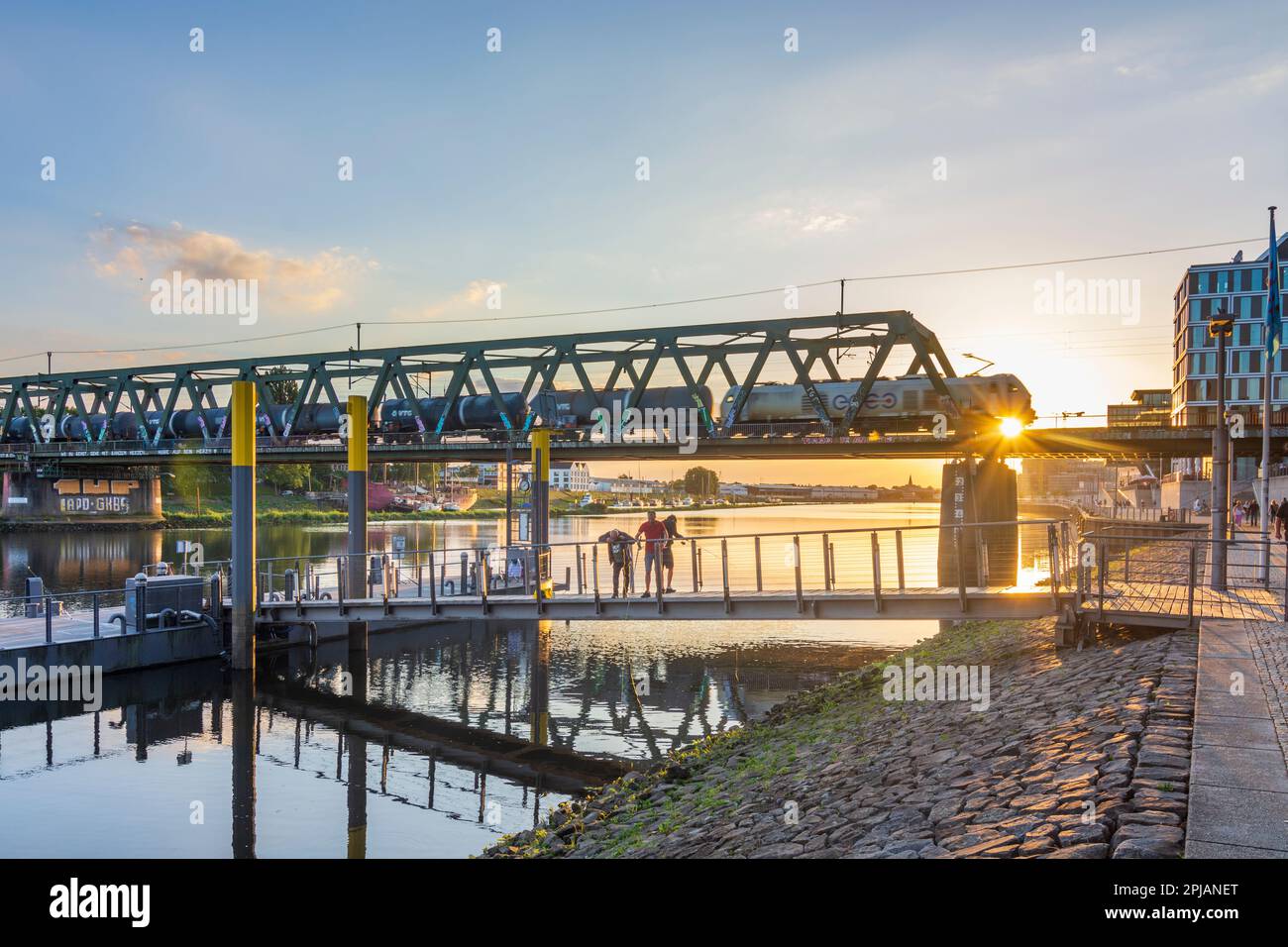 Bremen: river Weser, promenade Weserpromenade, bridge Eisenbahnbrücke, cargo train, sunset, angler in , Bremen, Germany Stock Photo