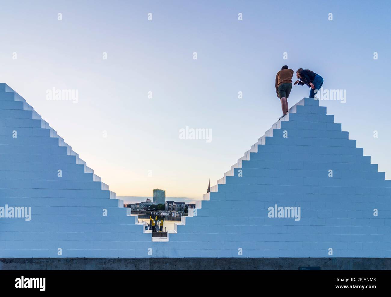 Bremen: sculpture 'Three Triangles' ('Outdoor Piece for Bremen'), by artist Sol LeWitt, persons climb on it, river Weser in , Bremen, Germany Stock Photo