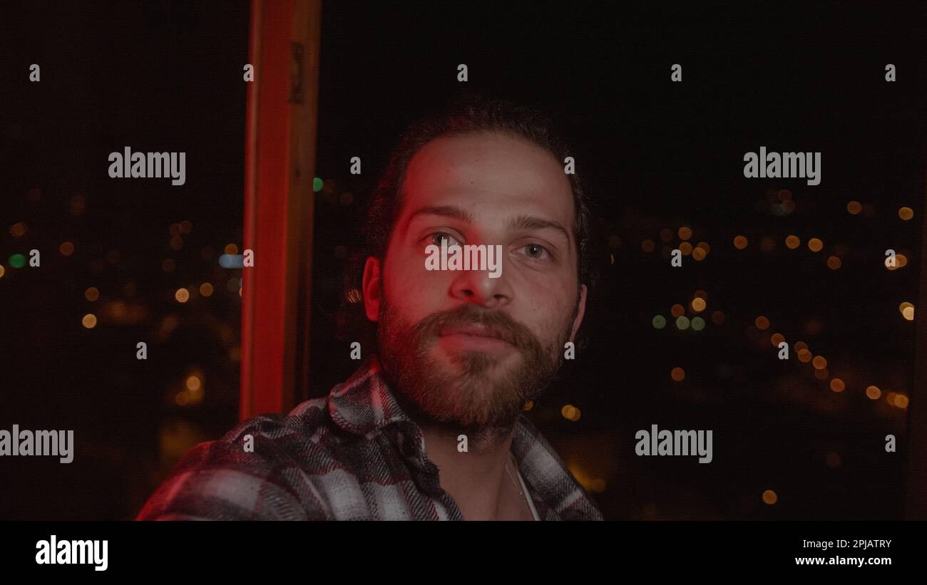 Masculine Young Handsome Man with Long Hair and Beard in Checked Shirt Video Calls on Smartphone in a Stunning Home with a View Stock Photo