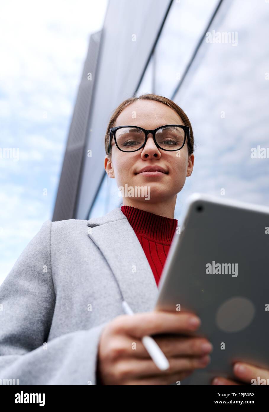 Female entrepreneur wearing glasses holding digital tablet in hands. Stock Photo