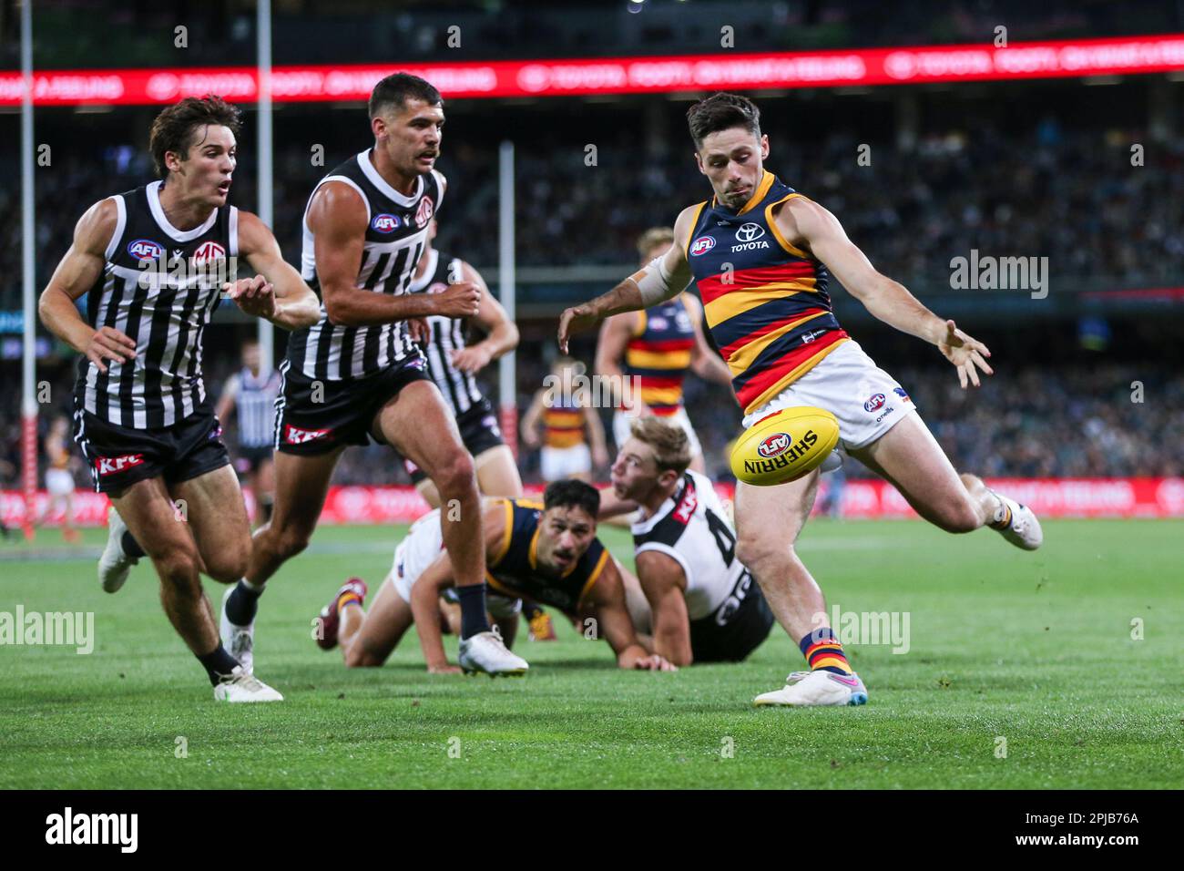 Chayce Jones of the Crows kicks past Connor Rozee and Riley Bonner of the Power during the AFL