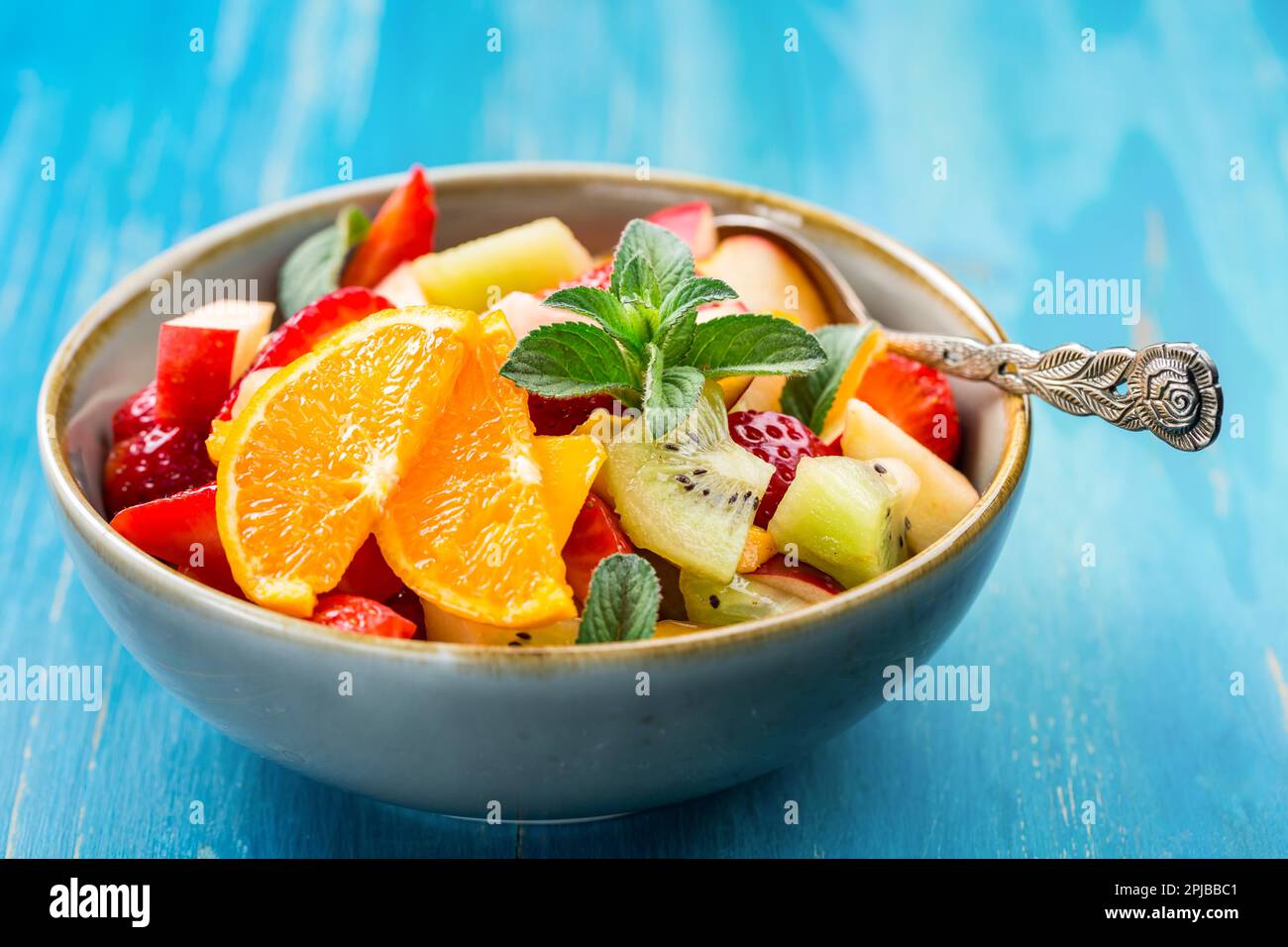 Fresh fruit salad full of vitamins for summer with mint on blue background Stock Photo