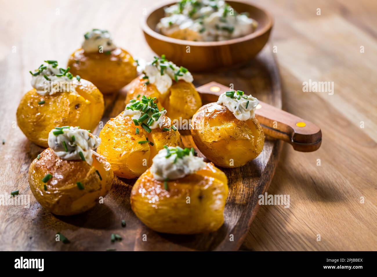 Small oven baked potatoes with sour cream with butter and chives Stock Photo