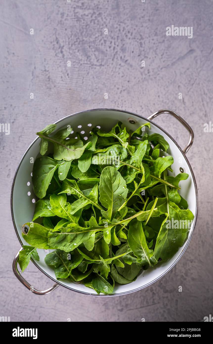 Fresh organic arugula leaves in white colander. Top view Stock Photo ...