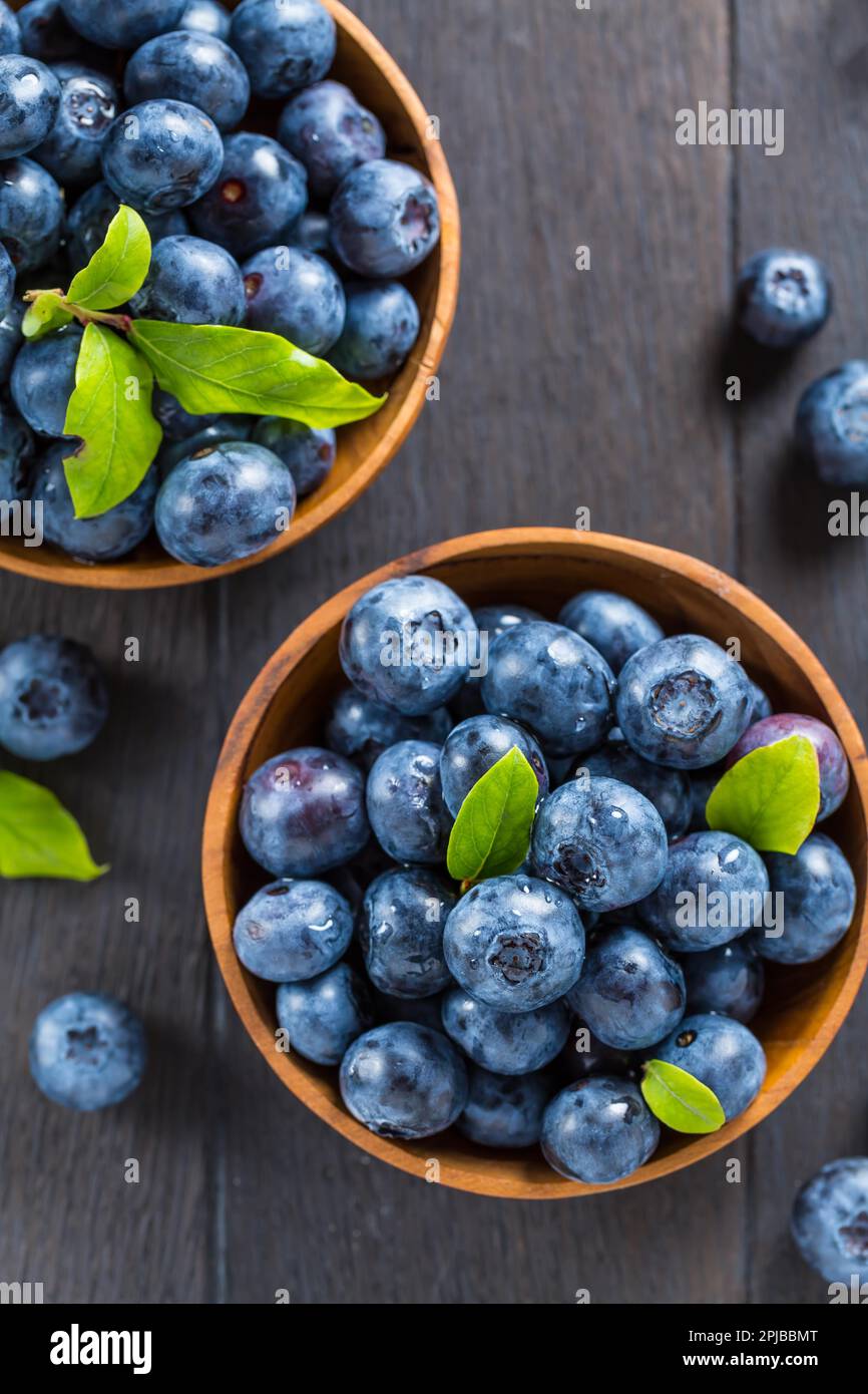 Fresh organic blueberry in bowl on wooden background. Healthy food concept, juicy wild forest berries Stock Photo