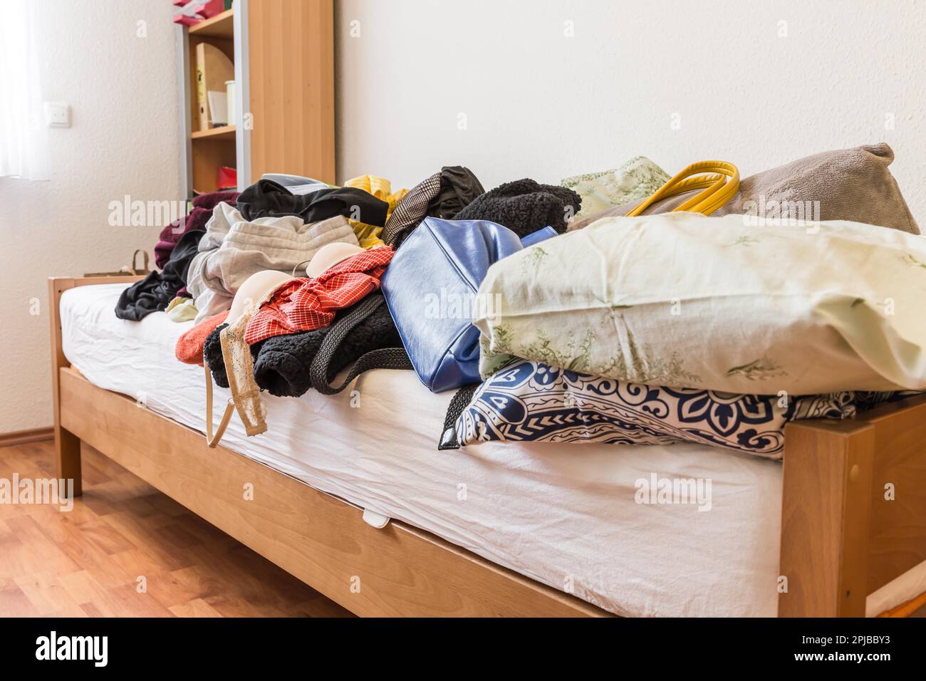 Messy teenager room. Untidy cluttered bed, dirty clothes. Compulsive