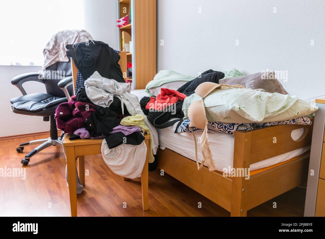 Messy teenager room. Untidy cluttered bed, dirty clothes. Compulsive