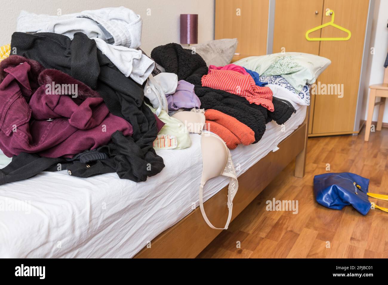 Messy teenager room. Untidy cluttered bed, dirty clothes. Compulsive Hoarding Syndrom Stock Photo