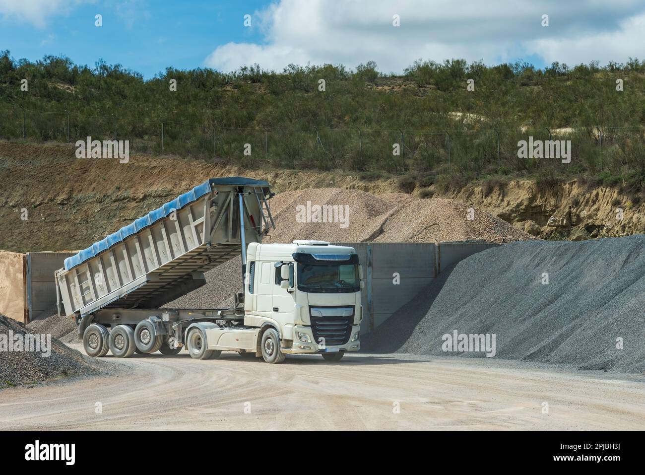Truck in an aggregate quarry with the dump raised after download. Stock Photo