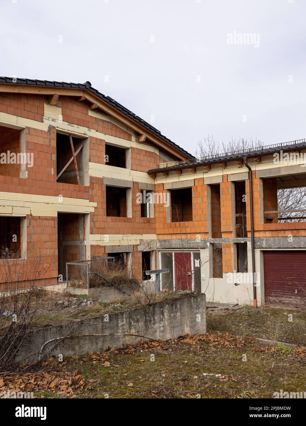 View of a two storey red brick shell of a residential home on a cloudy ...