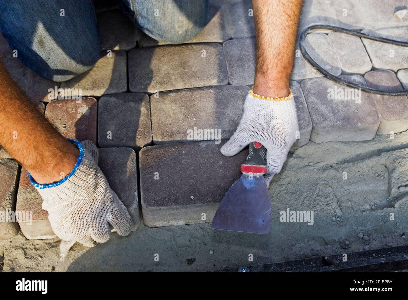 Construction worker fixing the pavestone on the roadtion worker installing stone blocks on pavemen Stock Photo