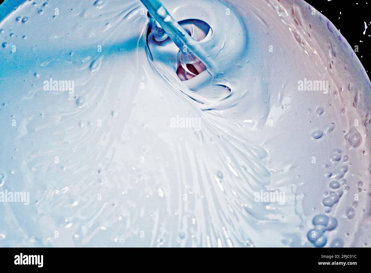 stir white paint with a violet pigment for painting walls Stock Photo