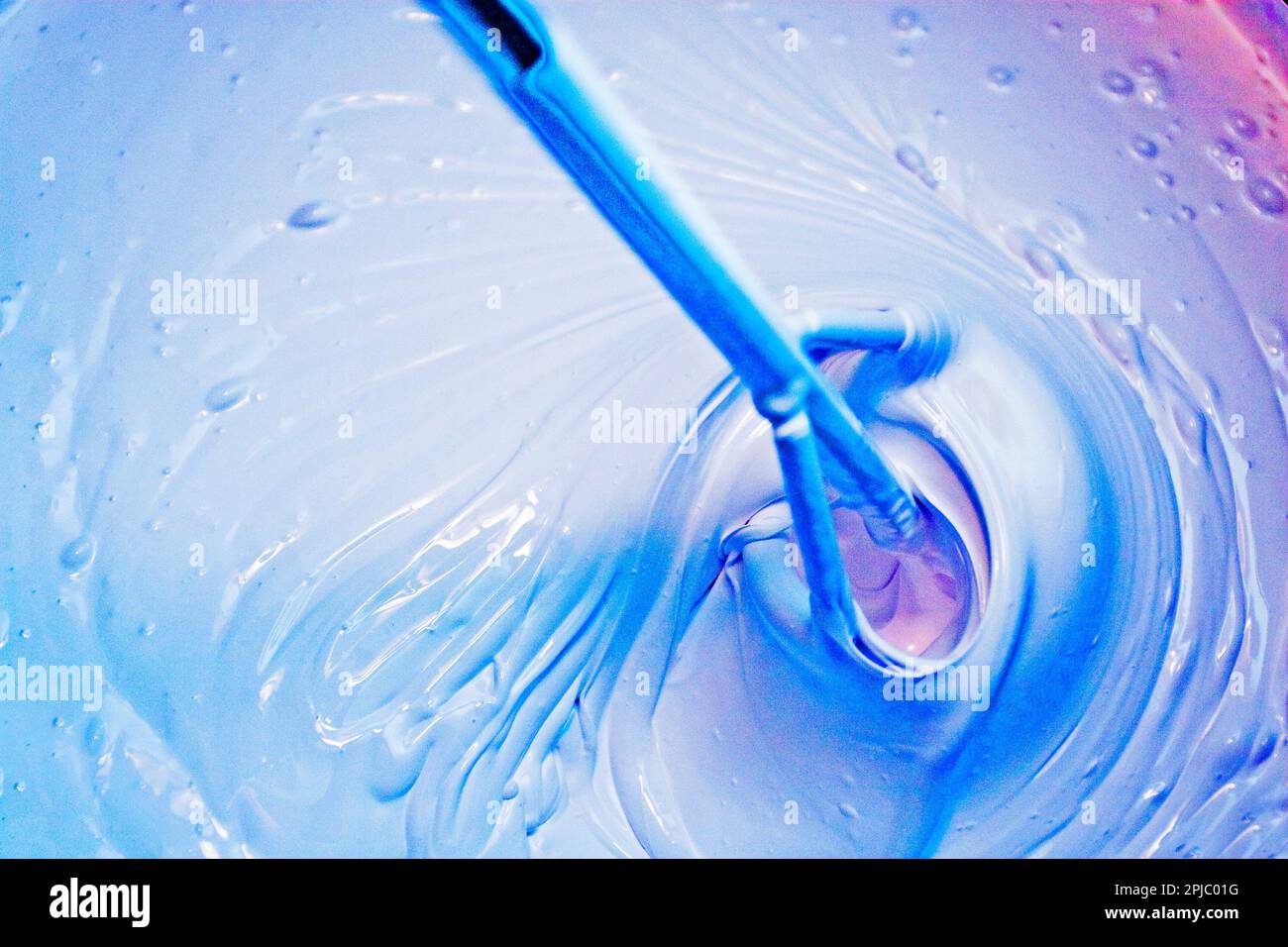 stir white paint with a violet pigment for painting walls Stock Photo