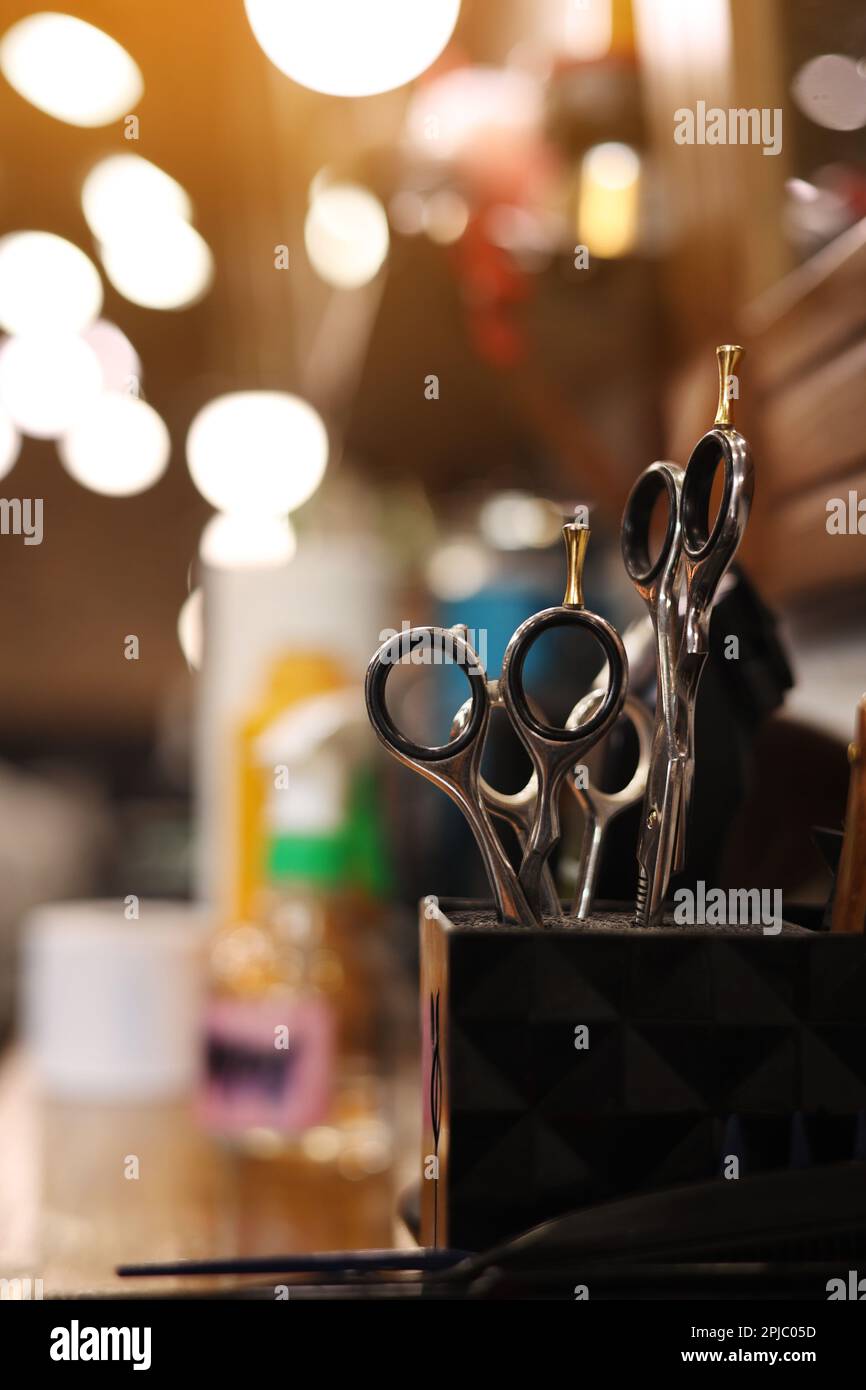Professional hairdressing tools. Various steel scissors and combs, hairbrushes on wooden table on barbers workplace at barbershop salon. The concept o Stock Photo