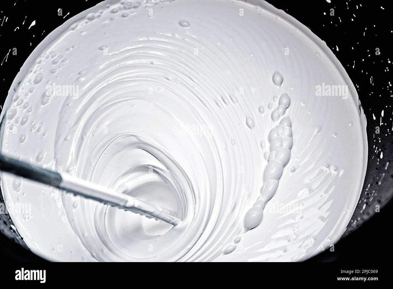 stir white paint to paint the walls Stock Photo Alamy