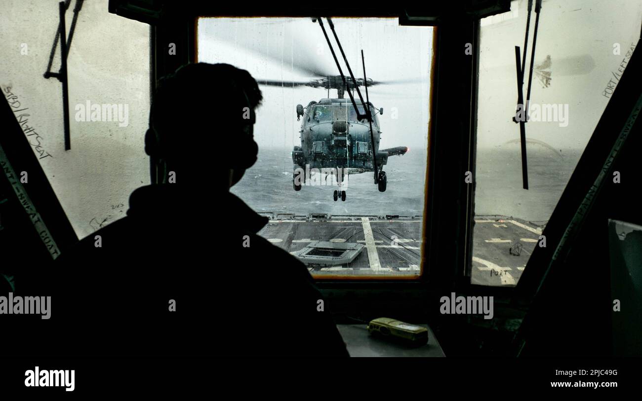 230320-N-NT811-0004 Pacific Ocean - (March 20, 2023) – Under the watchful eye of Lt.j.g. Greg Dawber acting as the helicopter control officer an SH-60R helicopter from Helicopter Maritime Strike Squadron Seventy-Eight (HSM 78) piloted by Lt. Trent Kurek and Lt. Dave Colville lands on the guided missile destroyer USS Sterett (DDG 104) after completing a surveillance exercise as part of surface warfare advanced tactical training (SWATT). Sterett is underway in the Pacific Ocean. SWATT is the Navy’s premier advanced tactical training even for the surface fleet to ensure units are competent, profi Stock Photo