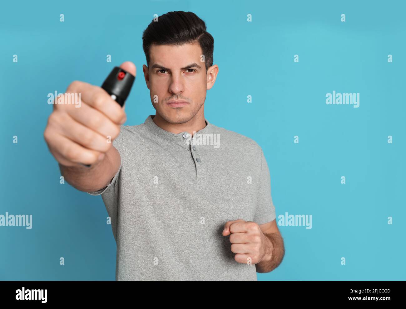 Man using pepper spray on turquoise background Stock Photo - Alamy