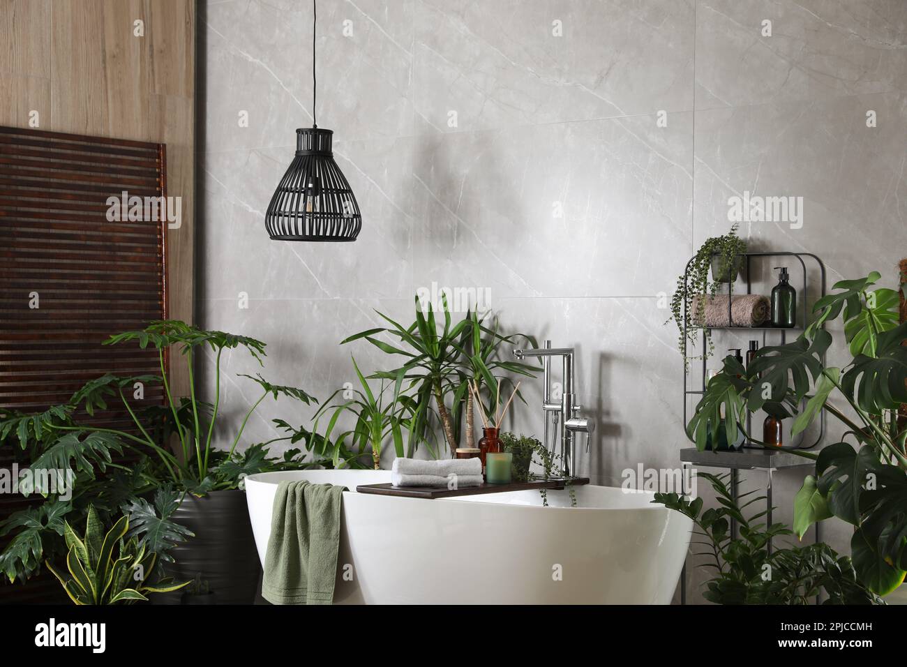 Modern white tub and beautiful green houseplants in bathroom. Interior ...