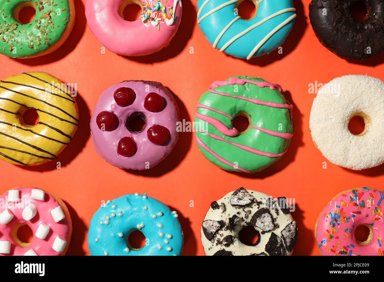 Sweet tasty glazed donuts on coral background, flat lay Stock Photo