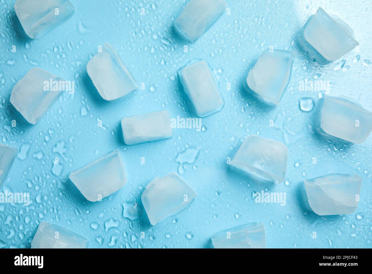 Cold ice and water drops on turquoise background, flat lay. Ingredient for refreshing drink Stock Photo