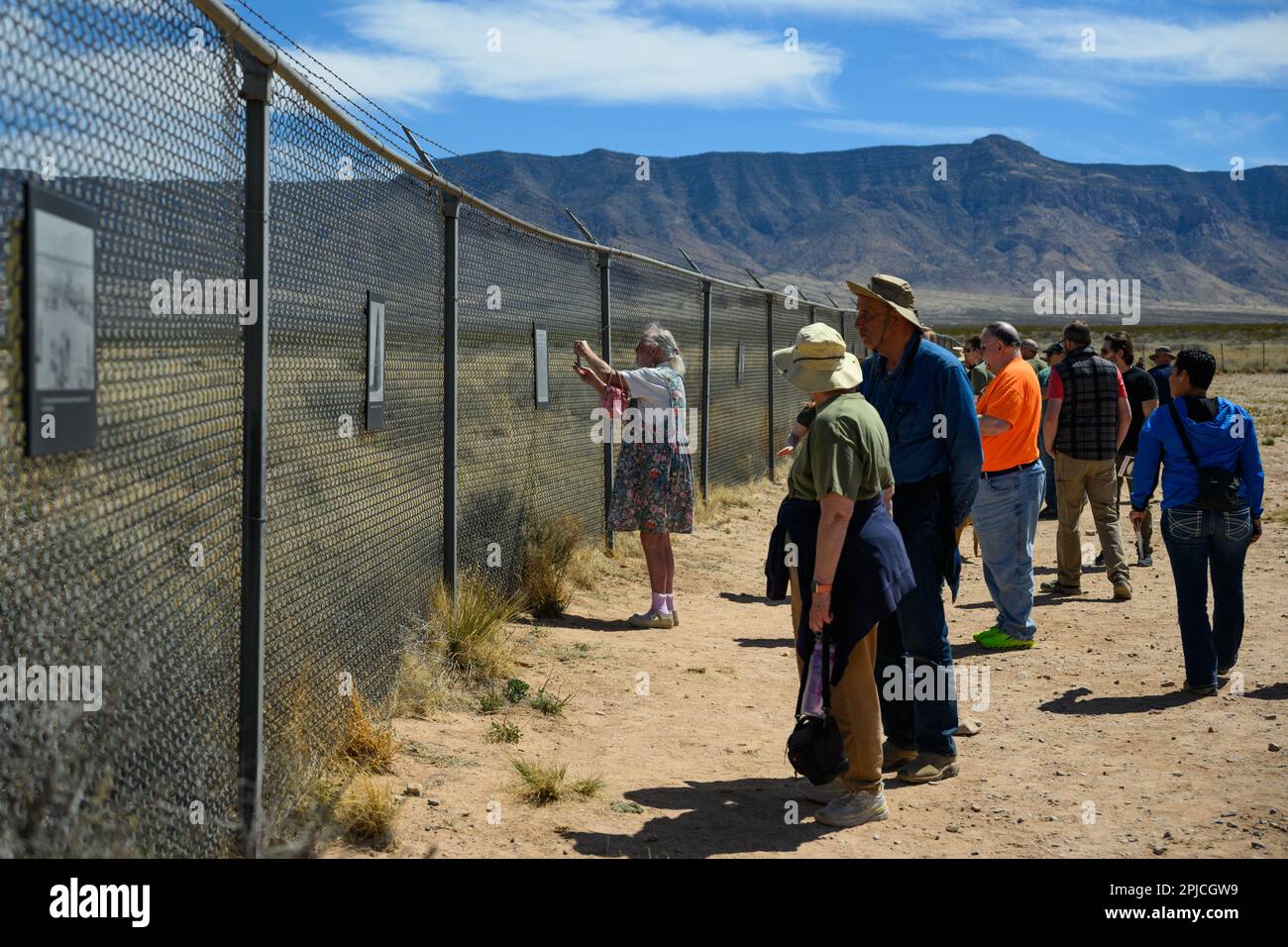 Tourists look at photographs hung on a fence from the first atomic bomb