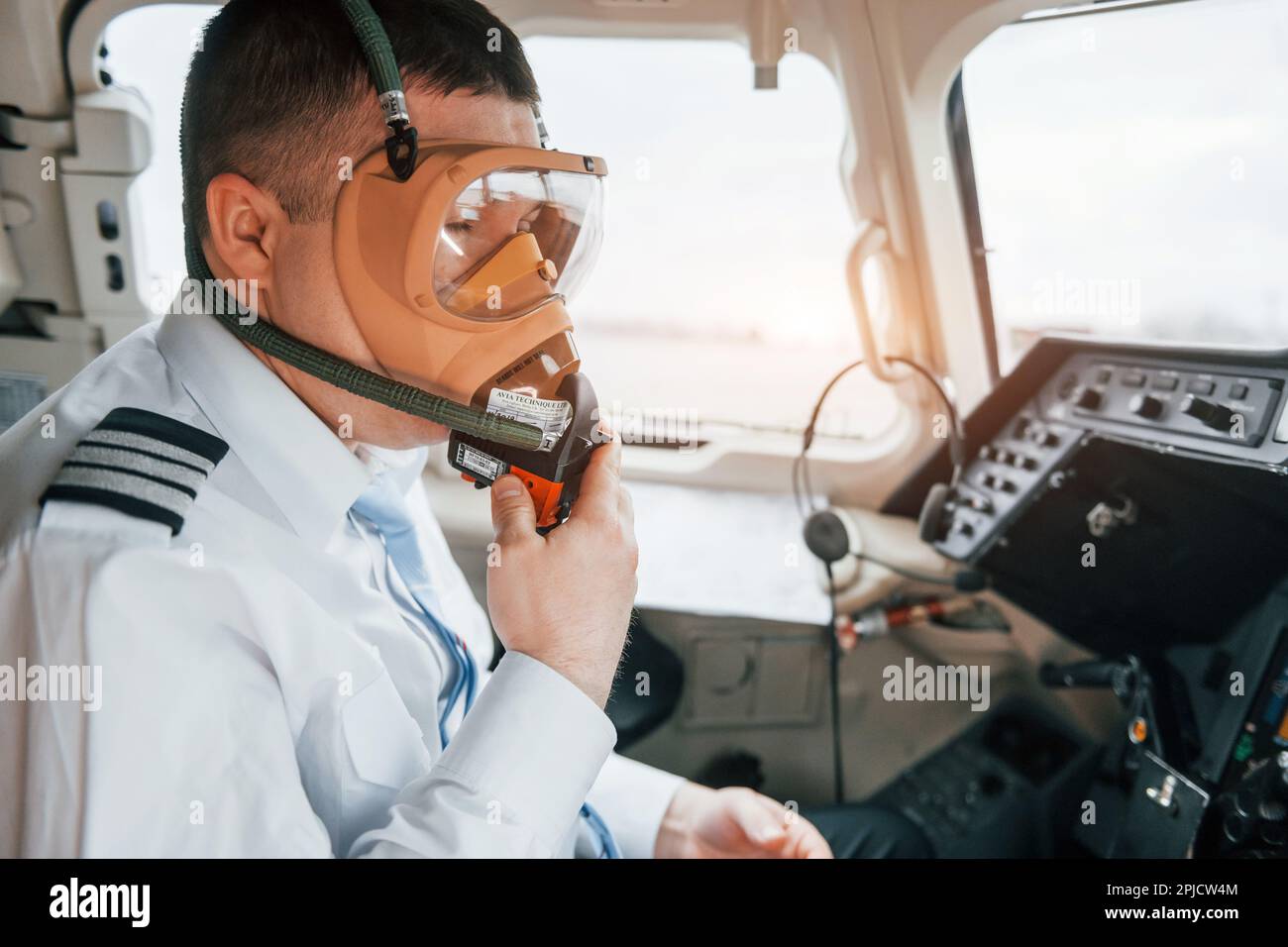 In oxygen mask. Pilot on the work in the passenger airplane. Preparing